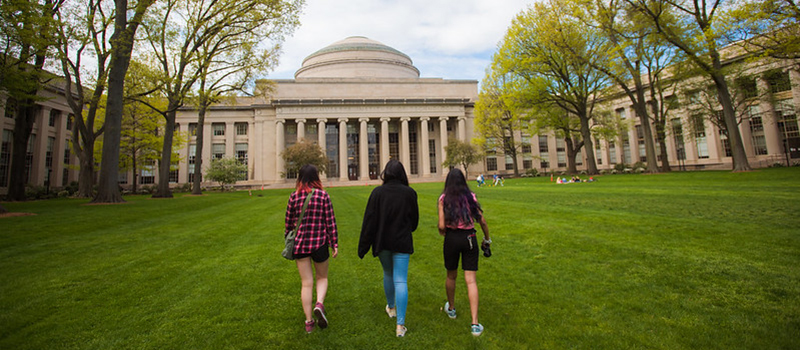 Three students walk across Killian Court toward the dome