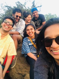 Chinmay and five friends group together, laughing, on a boulder.