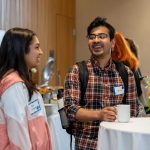 A woman and a man laugh together while enjoying refreshments at the event.