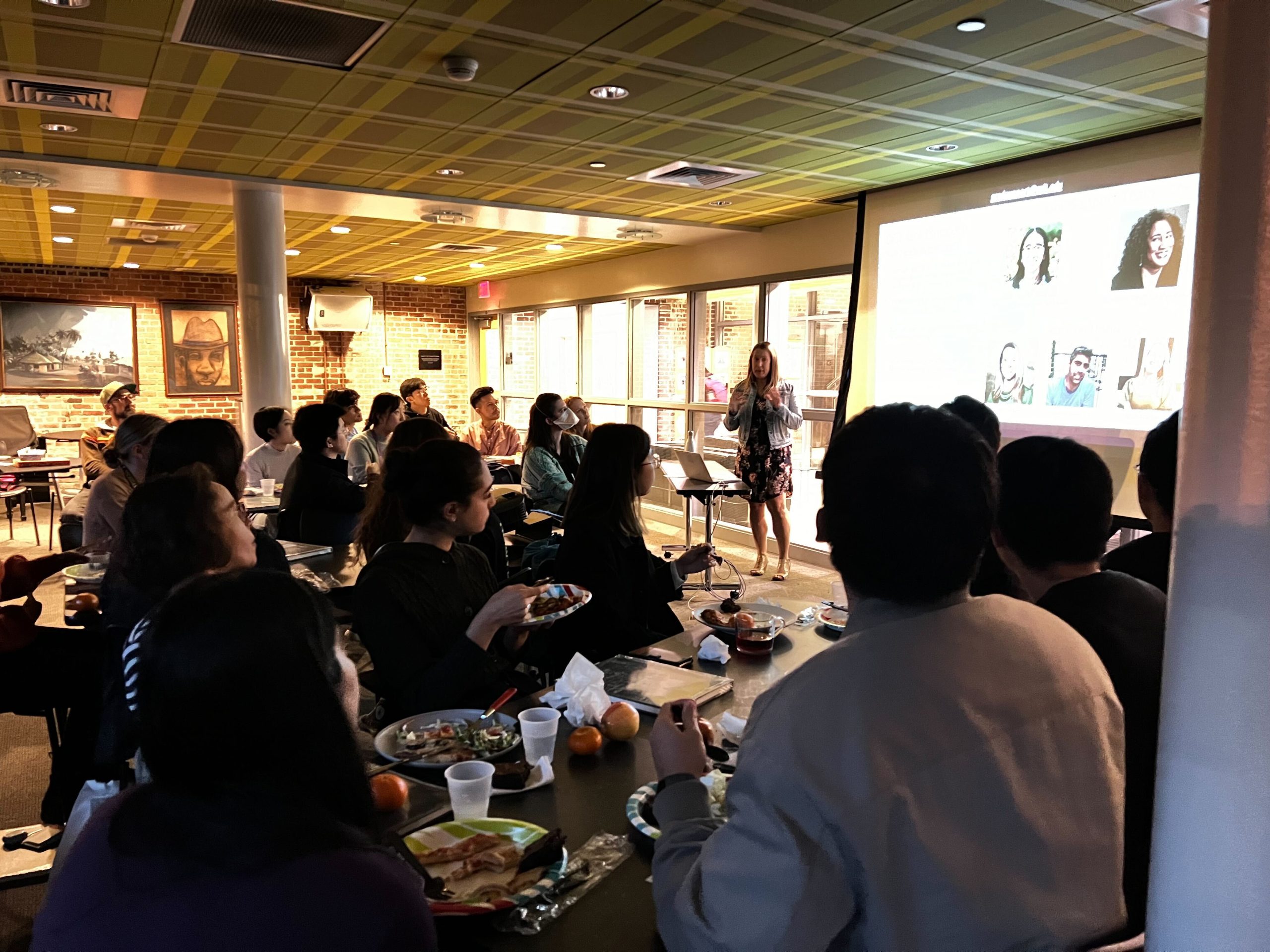 Beth Marois presents to a group of graduate students enjoying dinner in a cozy room.