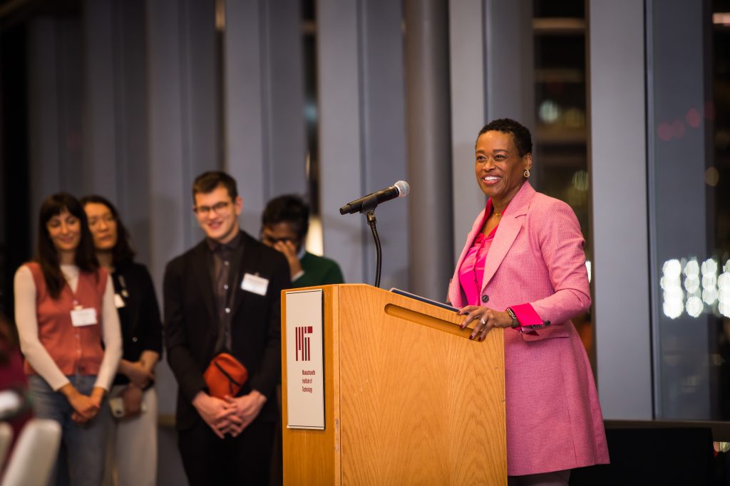 Chancellor Melissa Nobles speaks at a podium, students seen listening in the background.